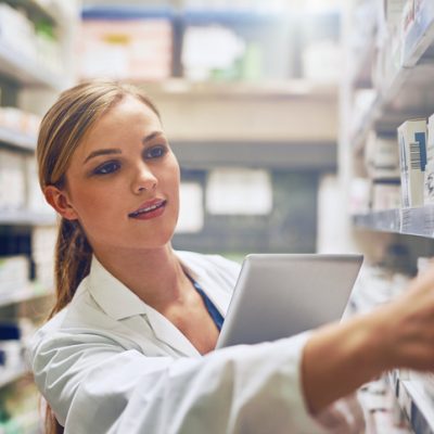 Shot of a pharmacist using her digital tablet while working in a isle